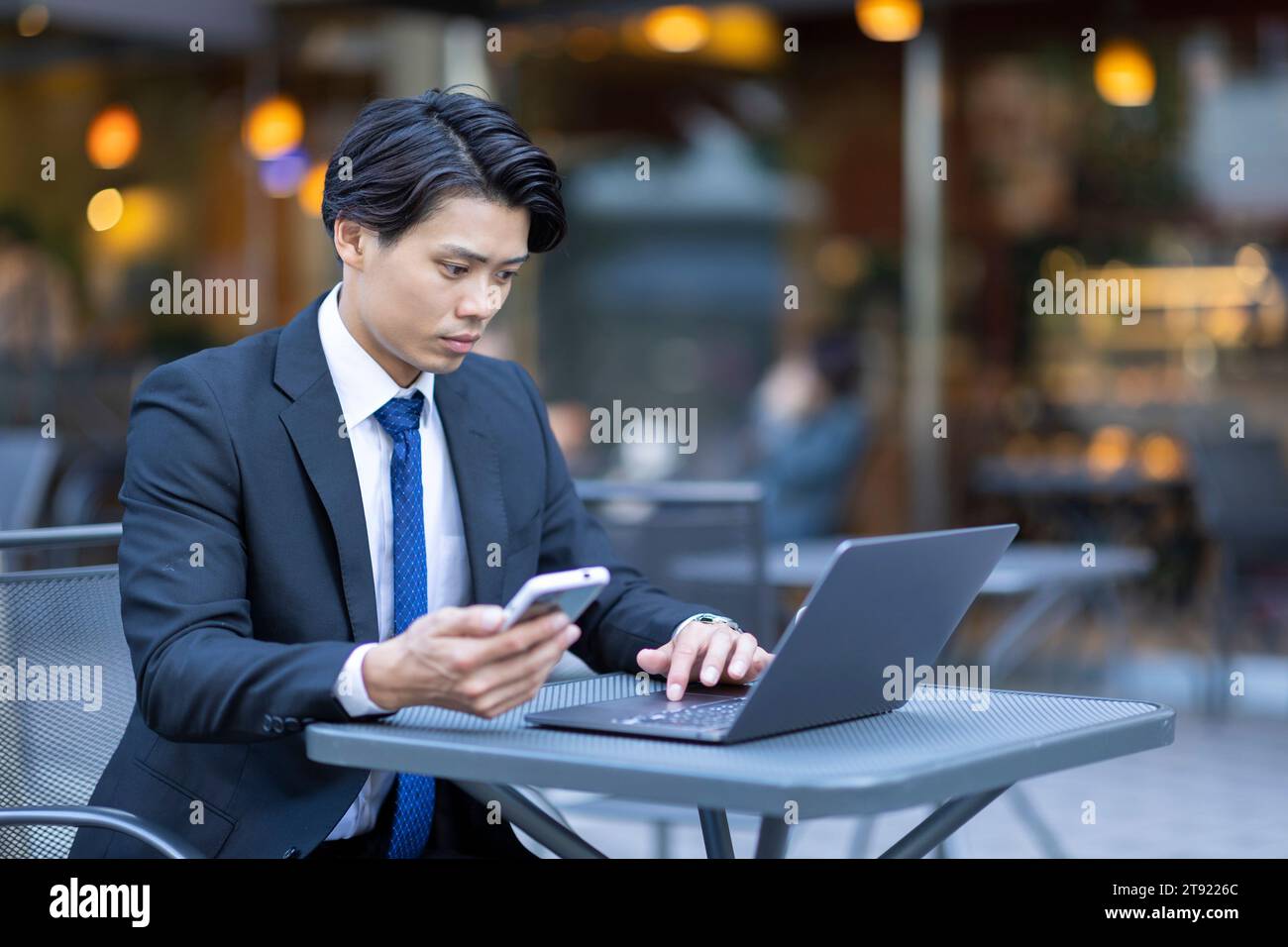 Geschäftsmann, der auf einen Computer auf der Terrasse schaut Stockfoto