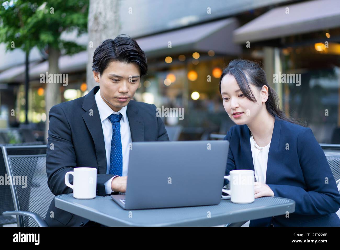 Ein Mann und eine Frau schauen auf einen Computer auf der Terrasse Stockfoto