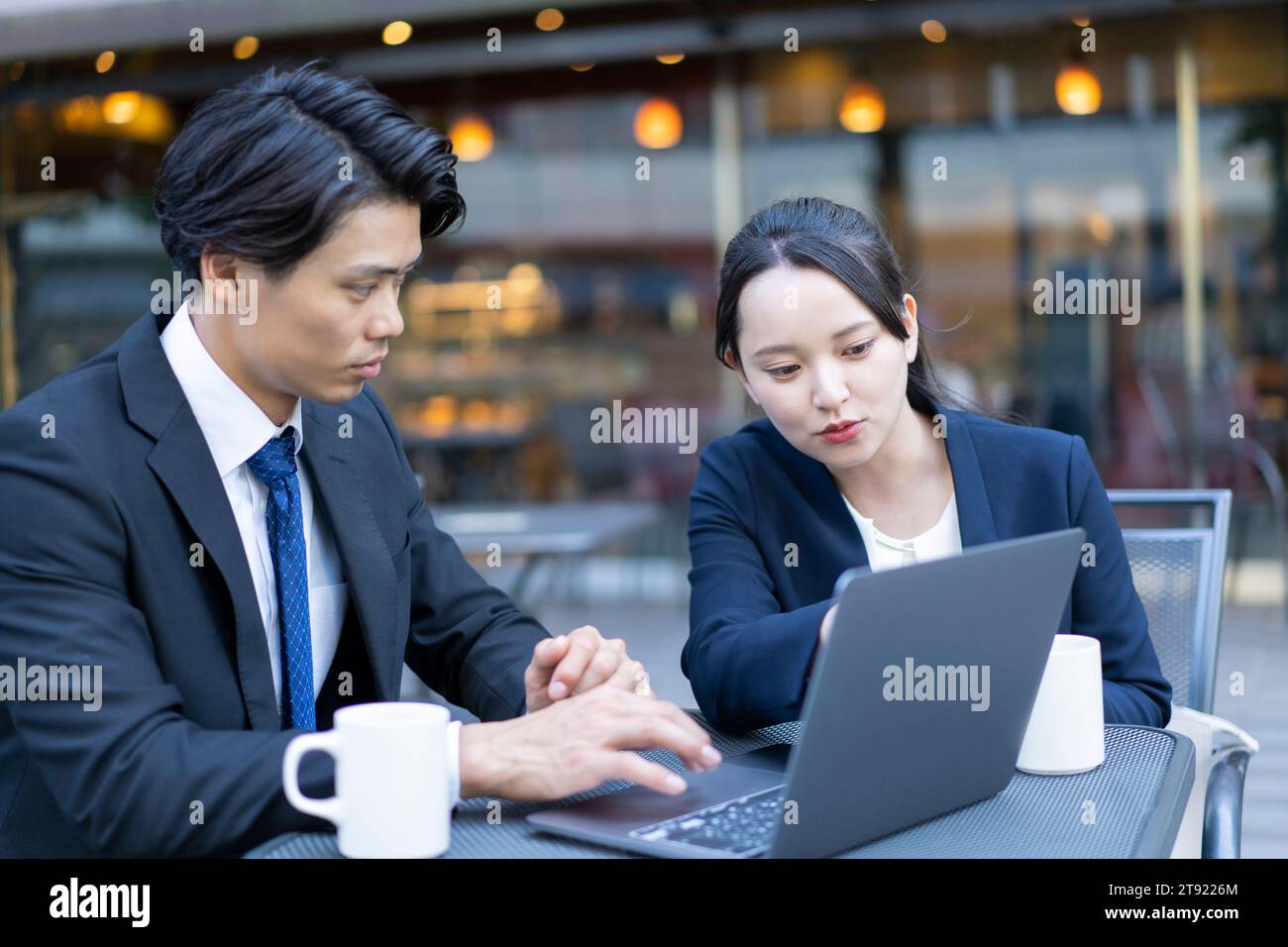 Ein Mann und eine Frau schauen auf einen Computer auf der Terrasse Stockfoto