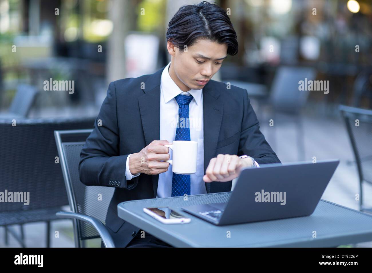 Geschäftsmann, der auf einen Computer auf der Terrasse schaut Stockfoto