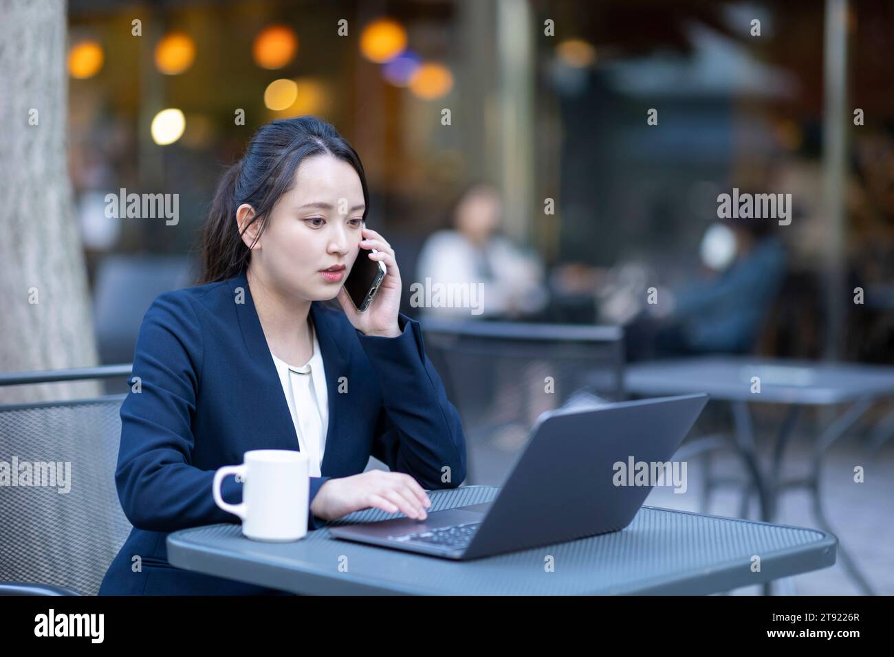 Geschäftsfrau, die auf einen Computer auf der Terrasse schaut Stockfoto