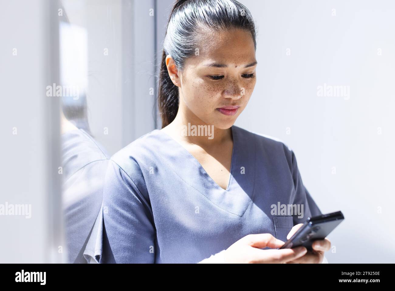 Birassische Ärztin mit Smartphon im Krankenhaus. Medizin, Gesundheitswesen, Kommunikation, Arbeit und Krankenhaus, unverändert. Stockfoto