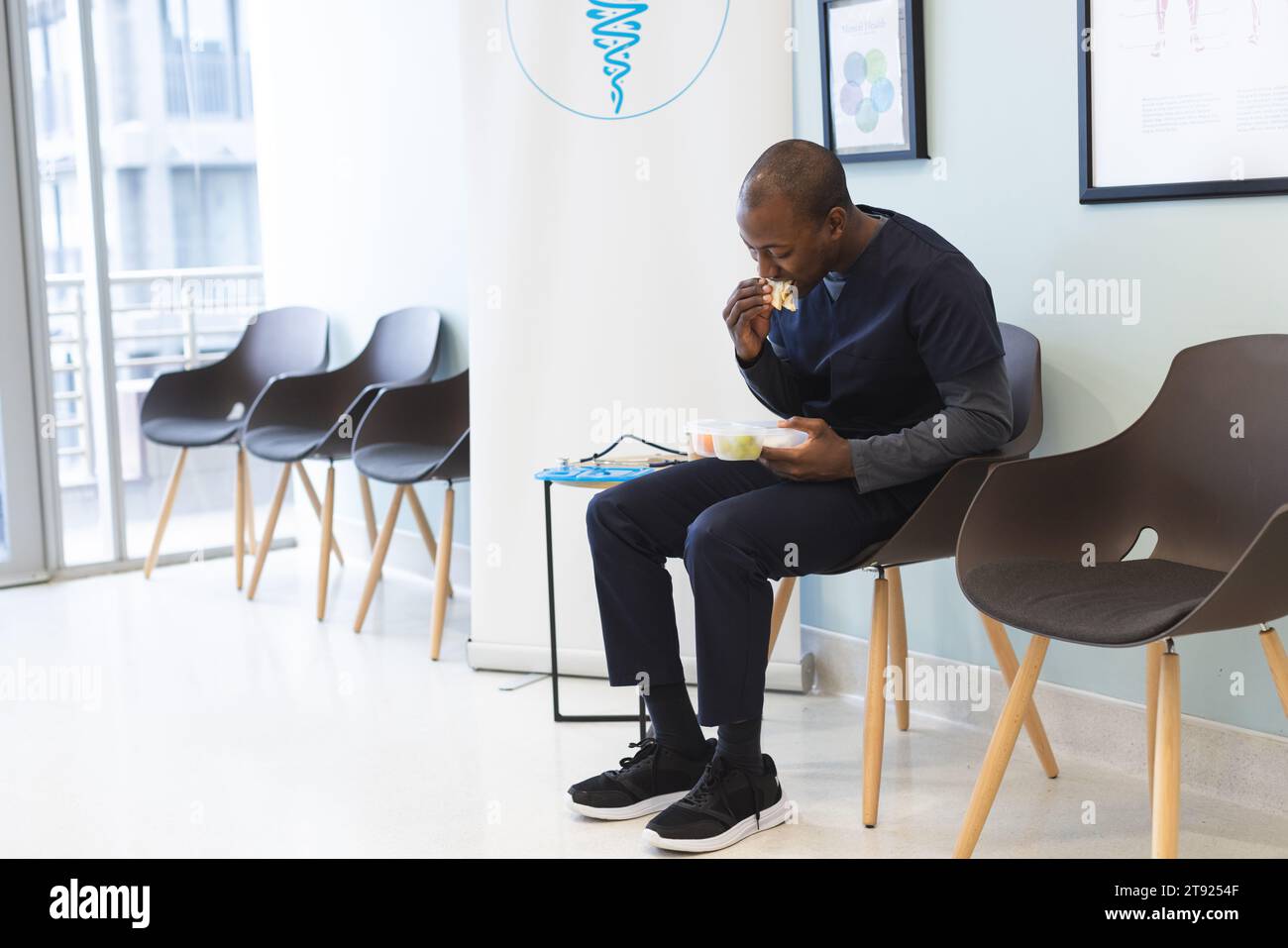 afroamerikanischer männlicher Arzt isst Essen zum Mitnehmen im Wartezimmer im Krankenhaus, Kopierraum Stockfoto