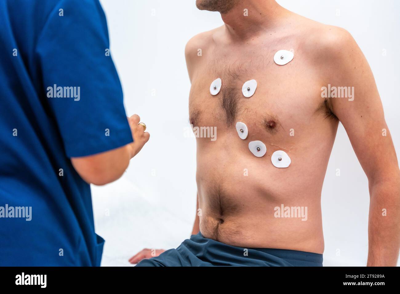 Arzt Kardiologe, der die Elektroden platziert, um ein Echokardiogramm bei einem Patienten im Krankenhaus durchzuführen Stockfoto