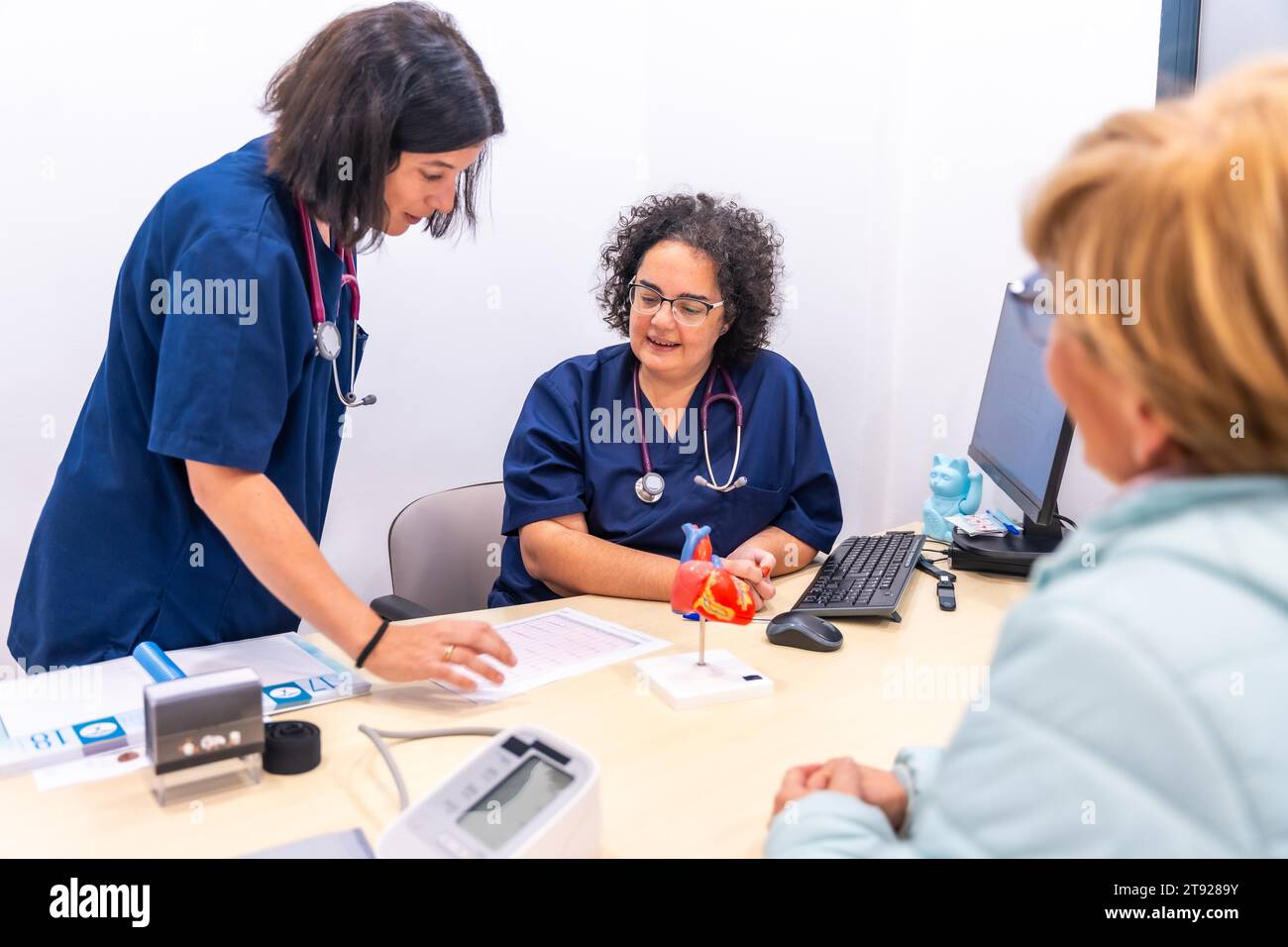 Pflegekraft zeigt dem Kardiologen in der Kardiologie-Klinik zusammen mit einem Kunden eine Analyse Stockfoto