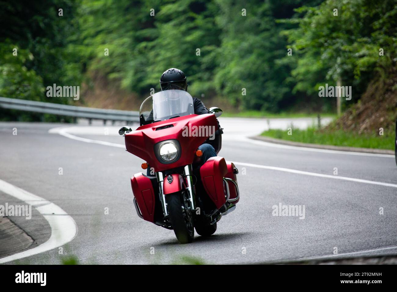 Motorradfahrer auf einem roten Cruiser Motorrad, das den Bergpass hinunter fährt Stockfoto