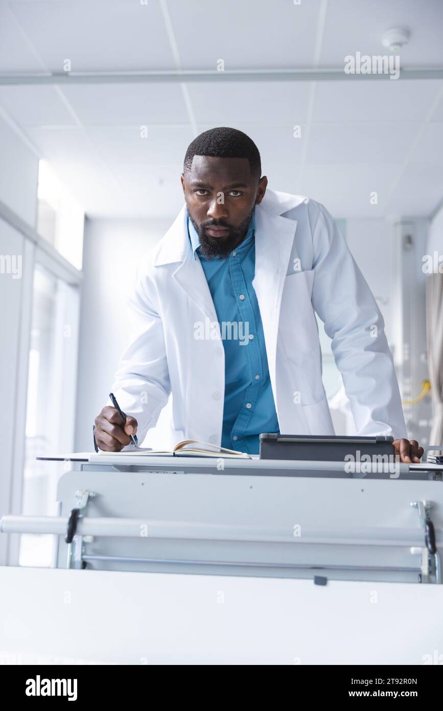 Porträt eines afroamerikanischen männlichen Arztes mit Tablette und Notizen im Krankenhauszimmer Stockfoto