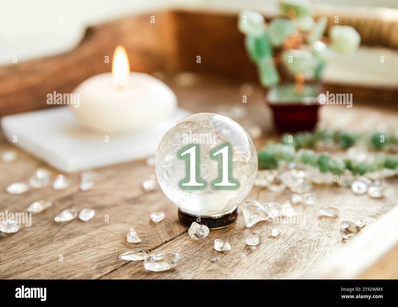 Nummer elf auf der Edelsteinkugel oder Kristallkugeln, bekannt als Kristallum orbis und Orbuculum. Natürliche klare Quarzkugel auf dem Ständer auf Holzschale zu Hause. Stockfoto