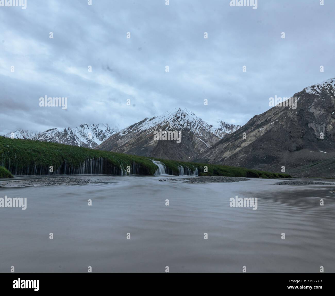 Landschaftsfoto eines schneebedeckten Berges mit lang belichtetem Wasser im Vordergrund. Stockfoto