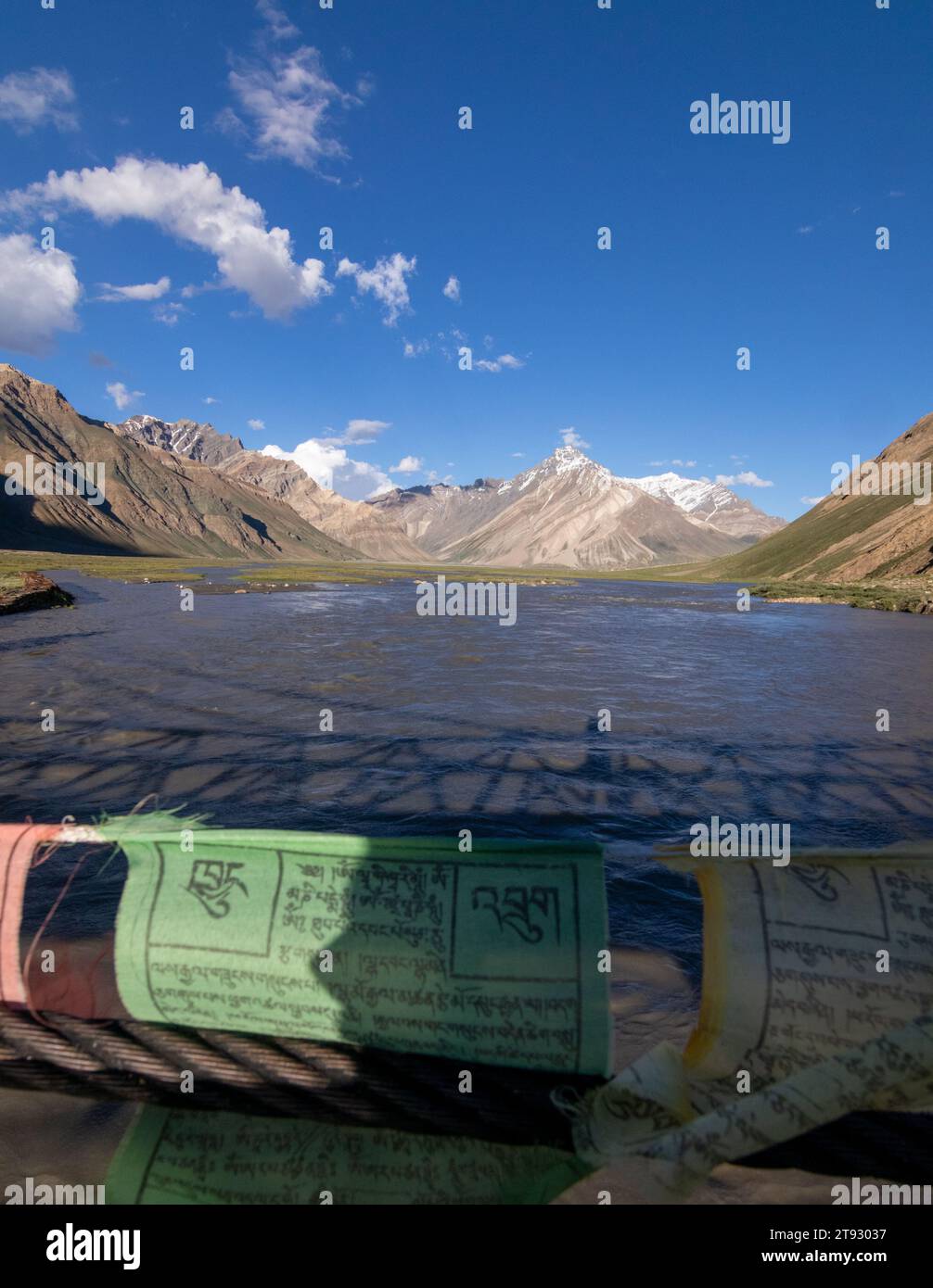 Landschaftsfoto eines schneebedeckten Berges von einer Brücke mit Gebetsfahnen im Vordergrund, während der Suru-Fluss durchfließt. Stockfoto