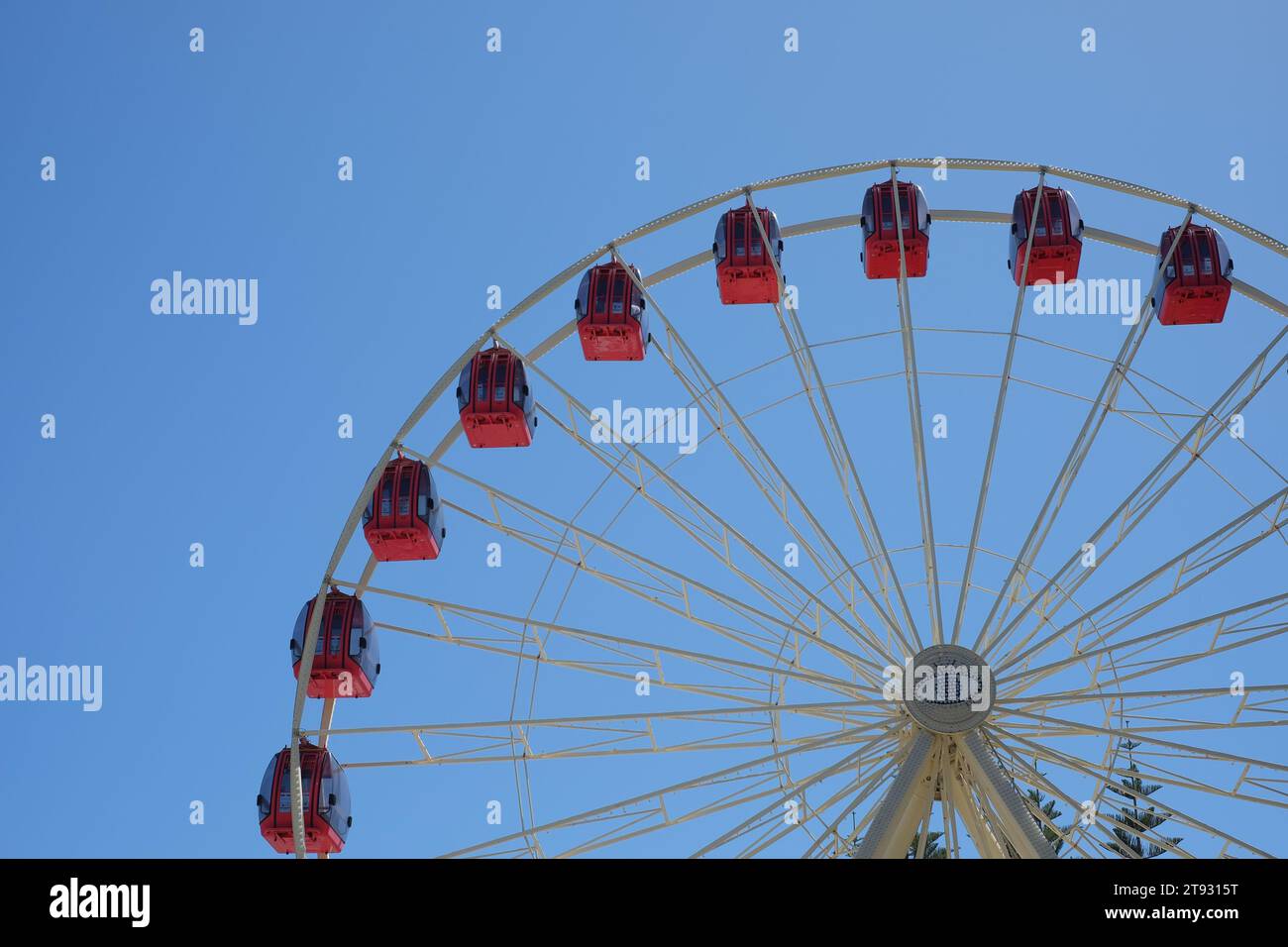 Rote Gondeln säumen einen Quadranten des Tourist Wheel Fremantle, einer beliebten Riesenrad-Attraktion, rot-weiß vor einem blauen Himmel Stockfoto