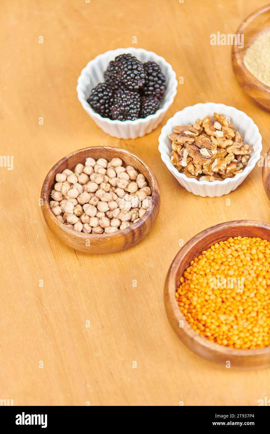 Brombeeren in der Nähe von Walnüssen und Linsen mit Kichererbsen in Schüsseln auf dem Tisch, pflanzliche Diäten, Blick von oben Stockfoto
