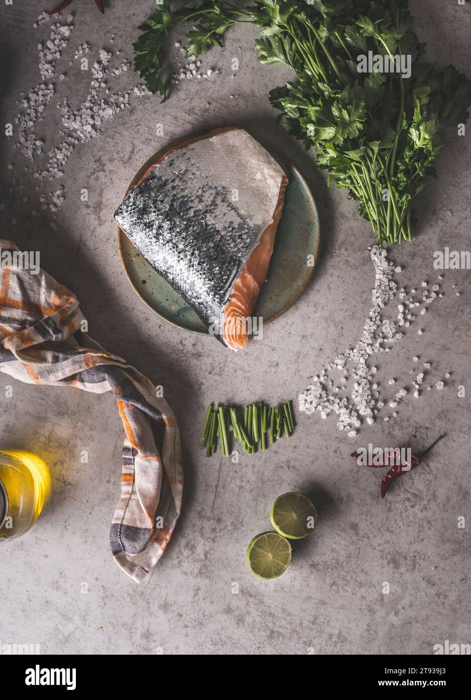 Lachszubereitung: Volllachs-Steak mit Schuppen am grauen Beton-Küchentisch mit Kräutern, Salz, Limette, Chili, Öl und Geschirrtuch. Vorbereiten Stockfoto