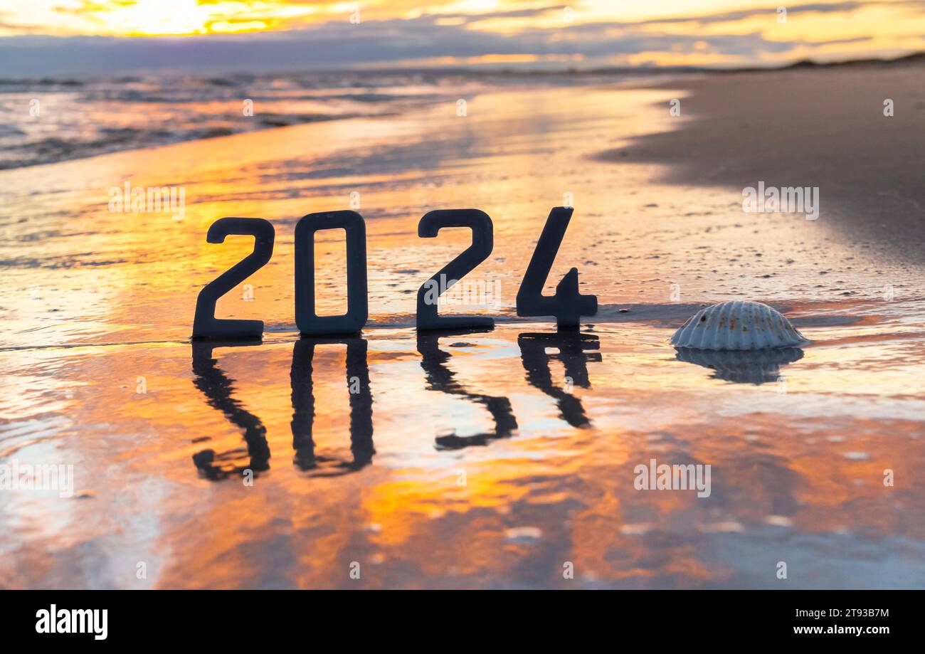 Happy New Year 2024 Neujahr 2024 Konzept mit Sonnenuntergang am Strand und die Zahlen 2024