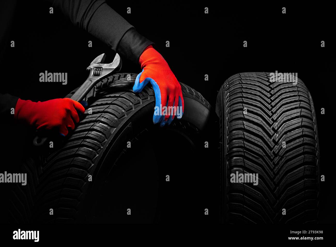 Winterreifen Service und Daumen hoch Hände des Mechanikers mit Schraubenschlüssel, Schraubendreher auf schwarzem Hintergrund Stockfoto