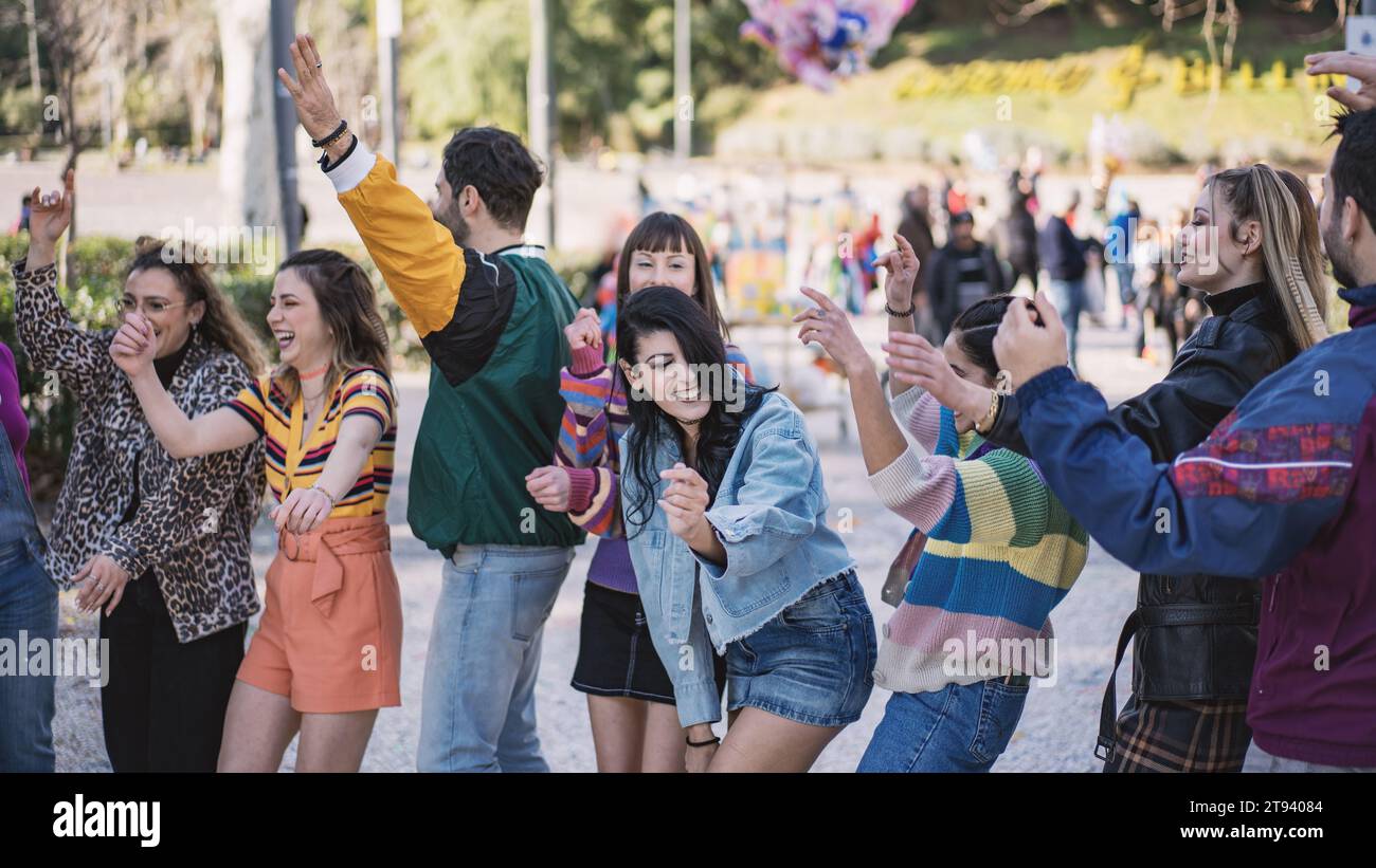 Gruppe fröhlicher junger Freunde, die in einem Stadtpark tanzen und feiern und gemeinsam einen sonnigen Tag genießen. Stockfoto