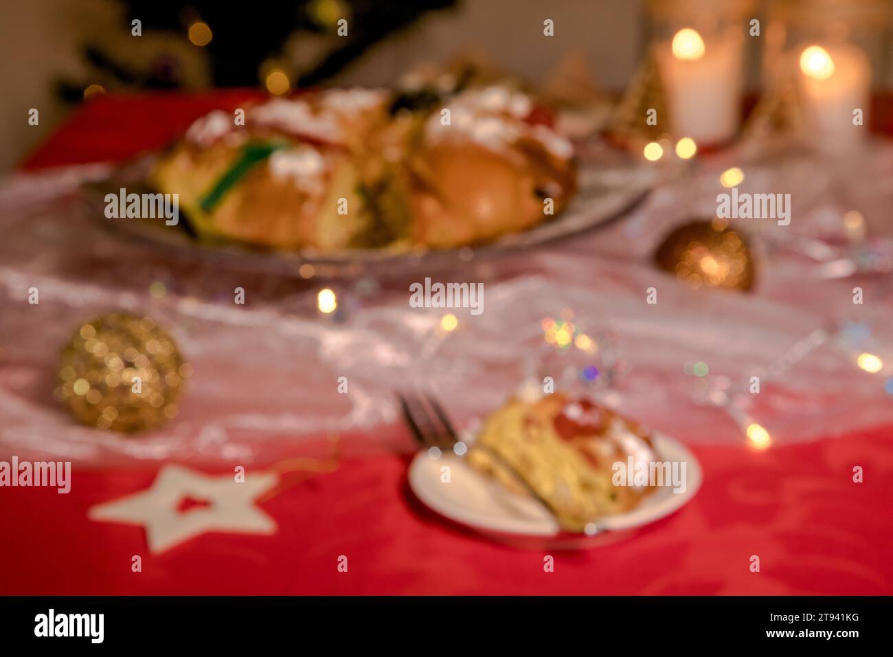 Verschwommenes Bild, das aber einen Tisch darstellt, der in weihnachtlicher Atmosphäre mit Lichtern, Kuchen und Farben der Weihnachtszeit dekoriert ist. Stockfoto
