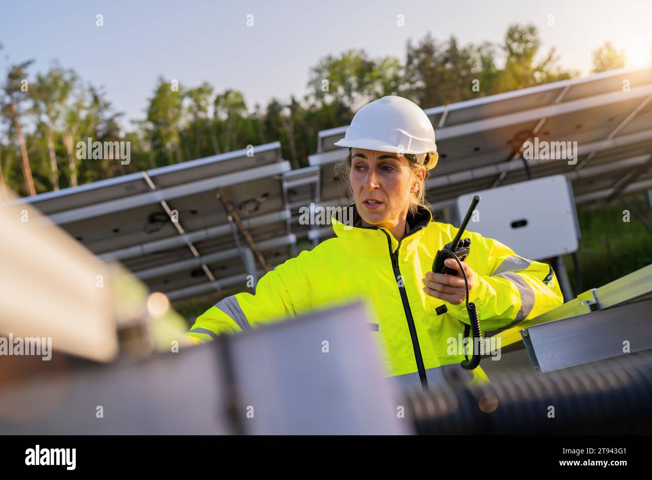Solartechniker mit Walkie-Talkie überprüft Solarpanel im Solarpark. Alternatives energetisches ökologisches Konzeptbild. Stockfoto
