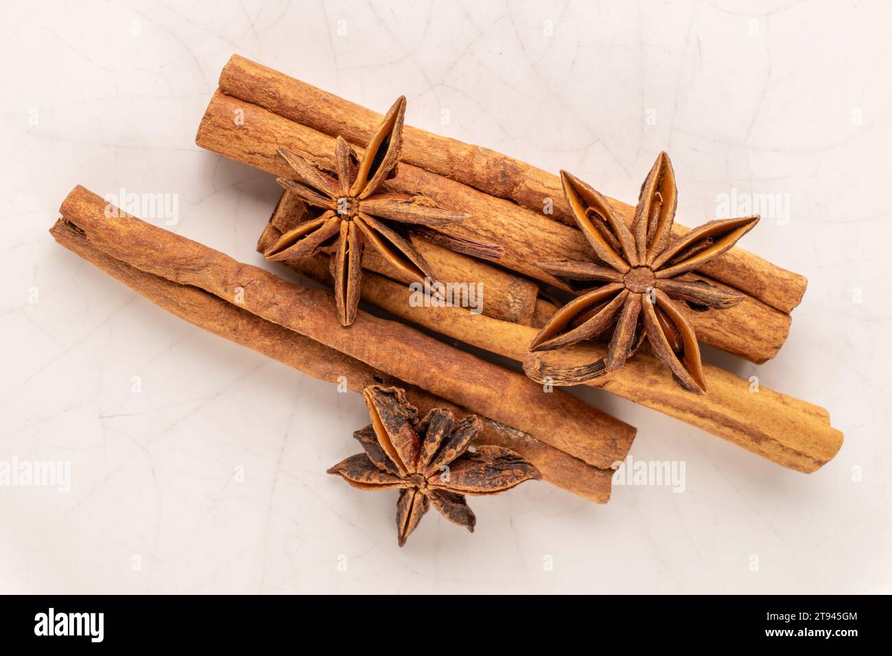 Drei Zimtstangen und drei Anissterne auf einer Keramikplatte, Makro, Draufsicht. Stockfoto