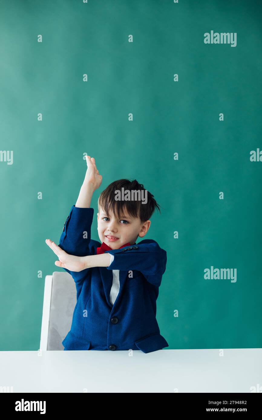 Junge Schüler Schuljunge hebt Hand, um Antworten im Klassenzimmer am Desk Education Knowledge zu beantworten Stockfoto