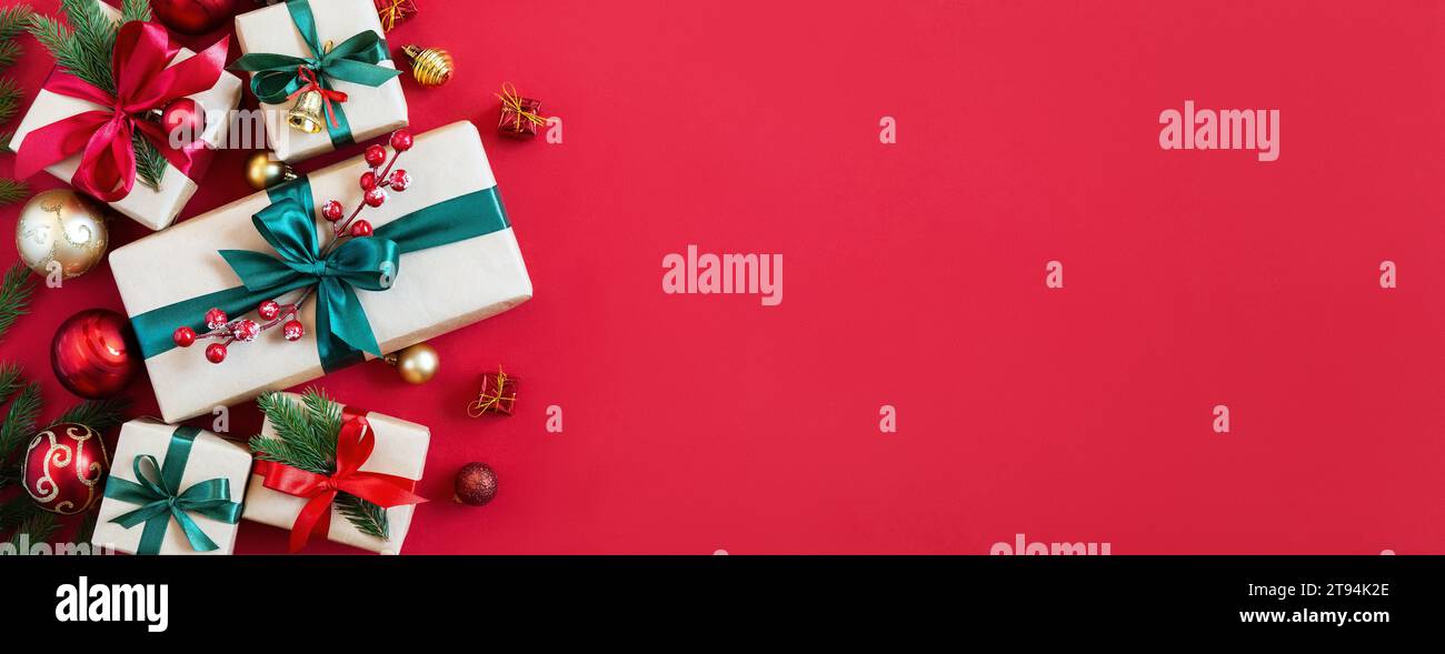 Feiertagshintergrund mit Geschenkboxen und Weihnachtsdekorationen. Roter Hintergrund für Weihnachtsfeiertage. Draufsicht mit Kopierbereich. Stockfoto