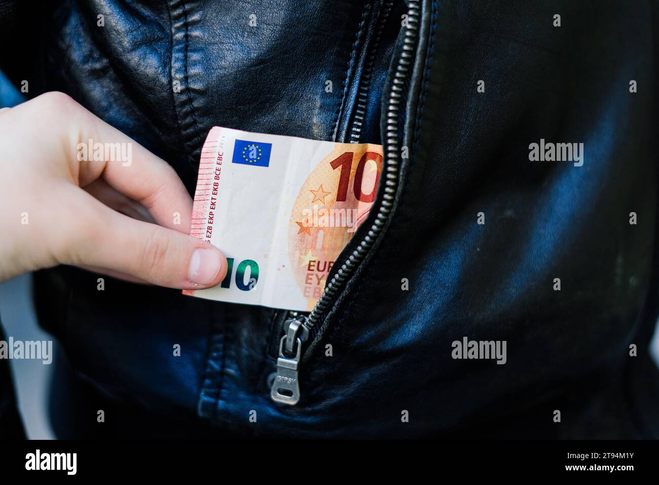 Die Hand zieht Papiergeld und Karte aus der Tasche. Ein Dieb hat einen Mann ausgeraubt. Bargelddiebstahl, kriminelles Konzept. Stockfoto