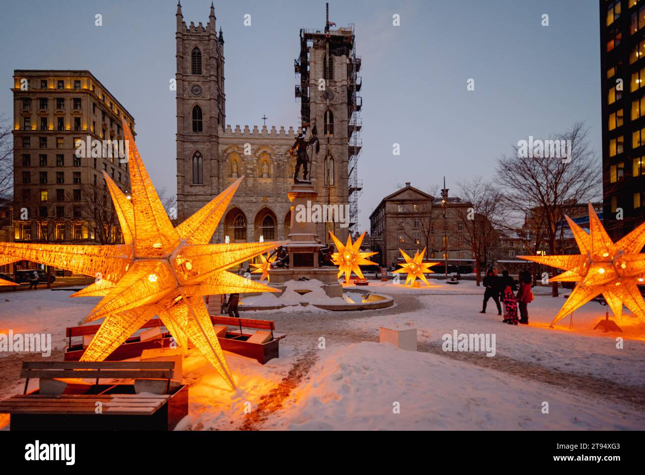 Montreal, Quebec, Kanada - 26. Februar 2023: Notre-Dame Basilika an einem düsteren Winterabend mit dekorativer gelber Beleuchtung und einigen Unkenntnissen Stockfoto