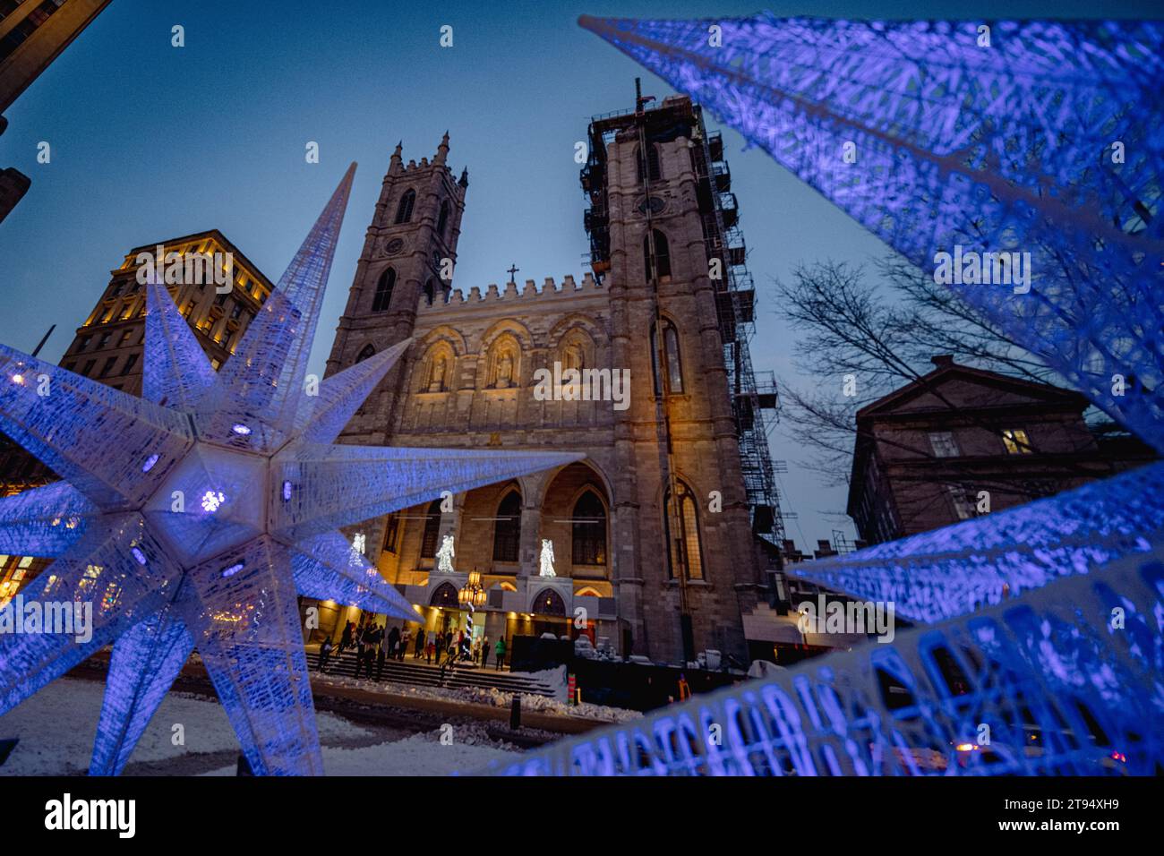 Montreal, Québec, Kanada - 26. Februar 2023: Die Basilika Notre-Dame wurde an einem düsteren Winterabend mit dekorativen lila Lichtern und einigen Unkenntnissen aufgenommen Stockfoto