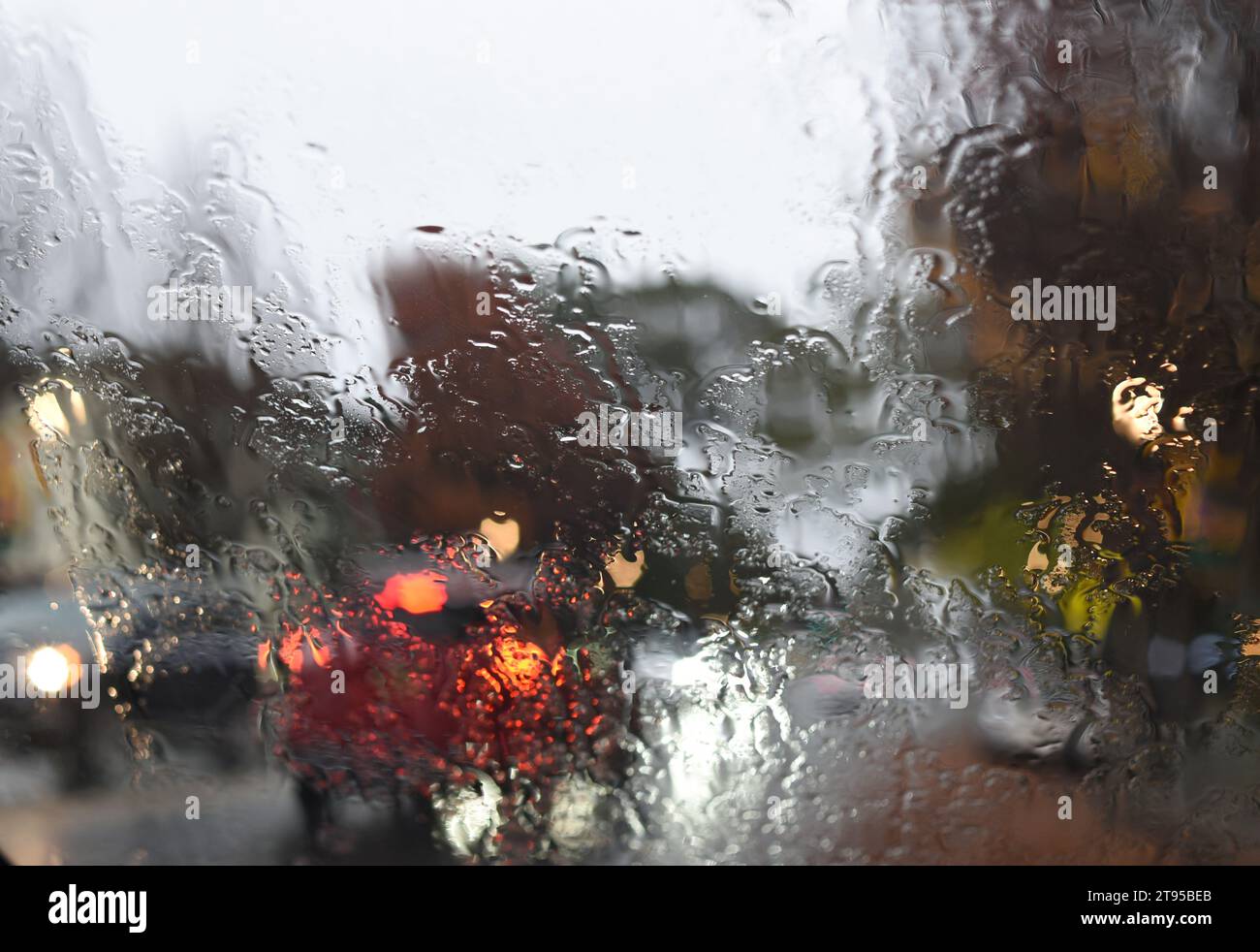 Der Verkehr wird durch eine regenbedeckte Windschutzscheibe betrachtet Stockfoto