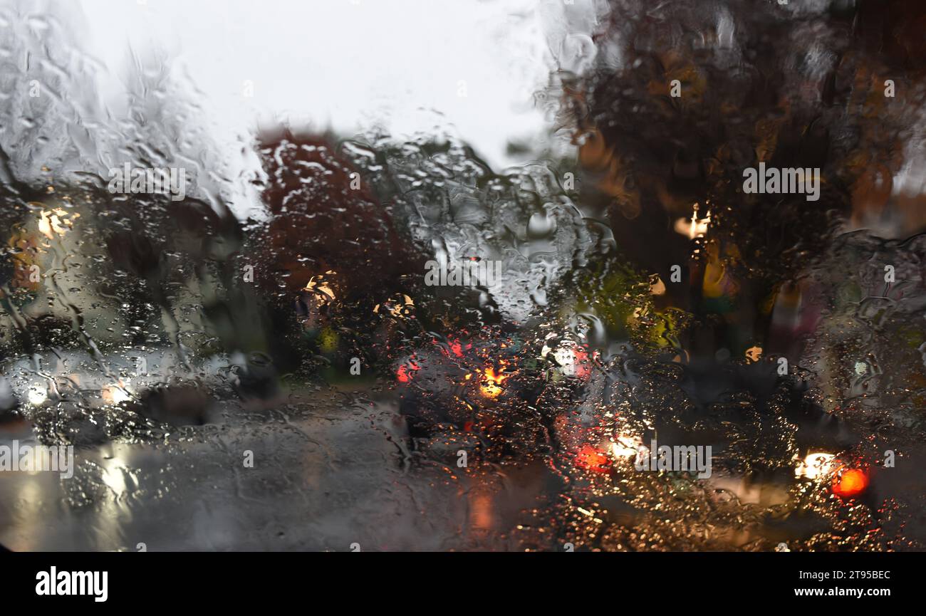 Der Verkehr wird durch eine regenbedeckte Windschutzscheibe betrachtet Stockfoto