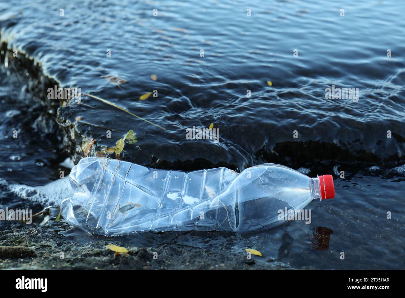Benutzte Plastikflasche in der Nähe von Wasser im Freien. Umweltverschmutzung Stockfoto