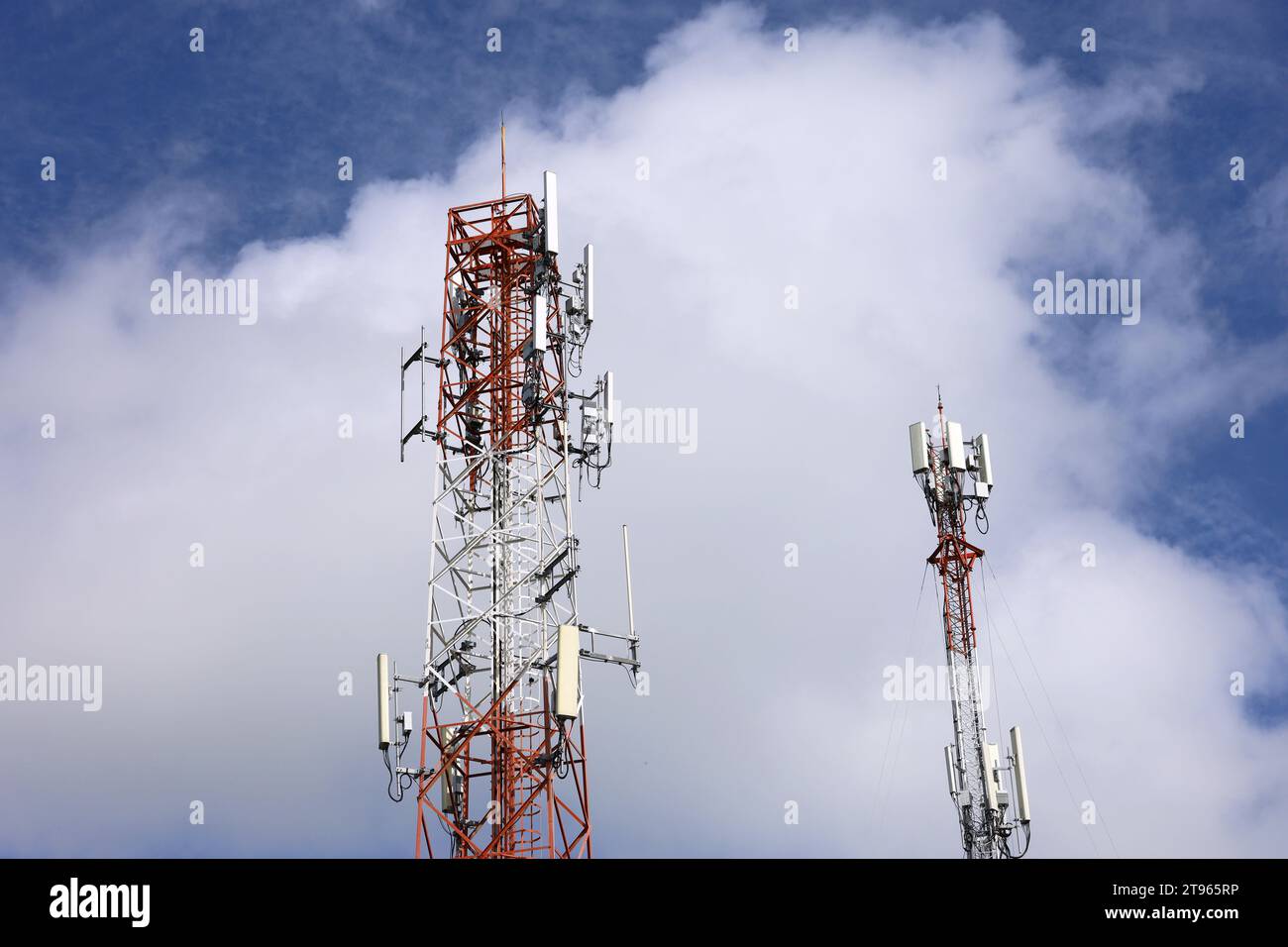 Mobile Telekommunikationstürme am blauen Himmel mit weißen Wolken. Mobilfunkturm mit Antennen und elektronischen Kommunikationsgeräten Stockfoto