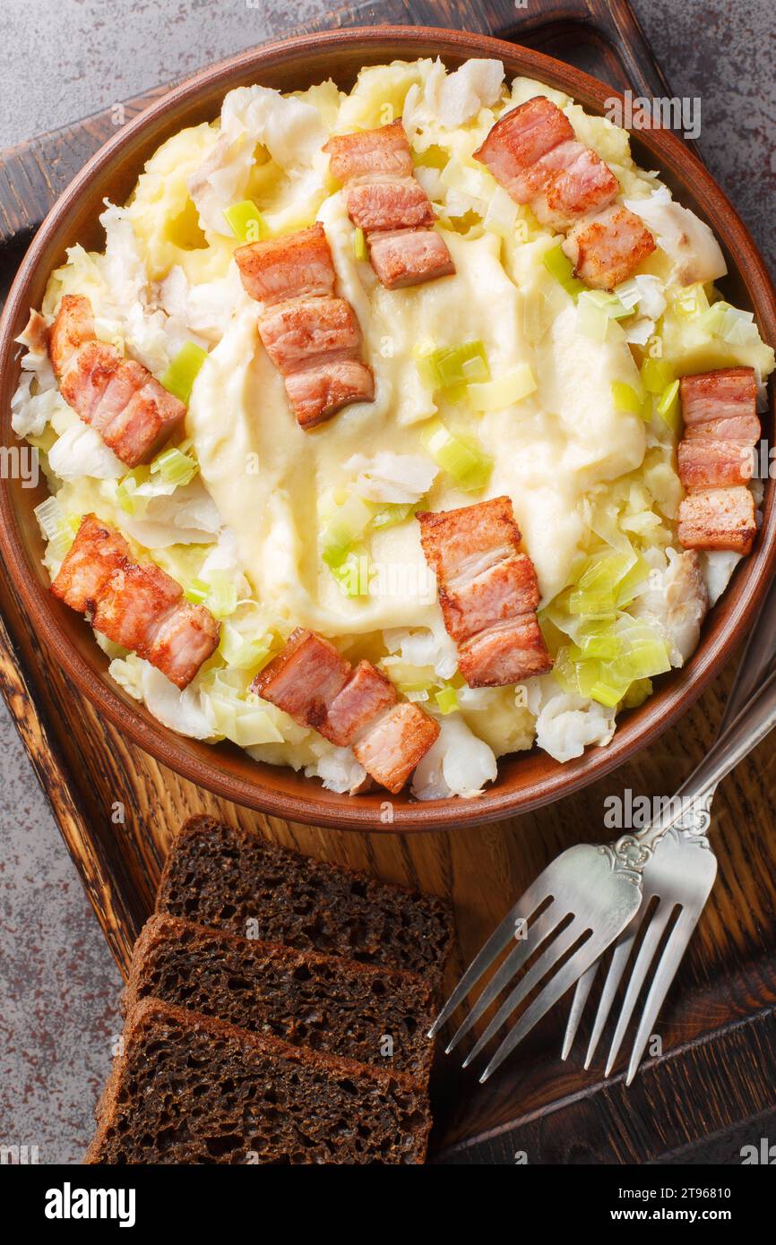 Norwegischer Frühlingsjau Plukkfisk mit gekochter Kartoffel, Lauch, Speck und Bechamelsoße auf einem Teller auf dem Tisch. Vertikale Draufsicht von oben Stockfoto