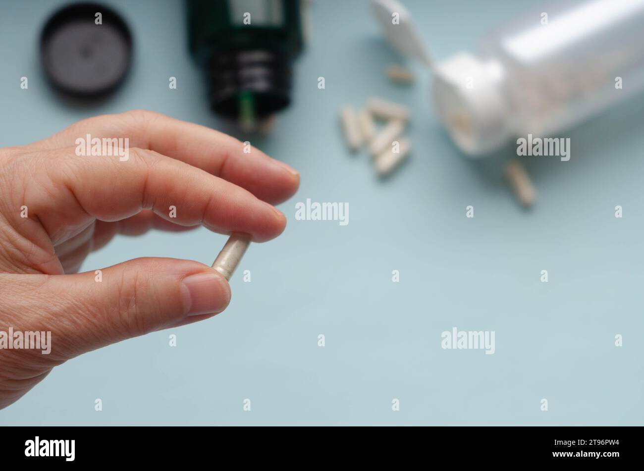 Pillen in der Hand und weiße Pille Flasche auf blauem Hintergrund. Konzentrieren Sie sich auf die Hand. Stockfoto