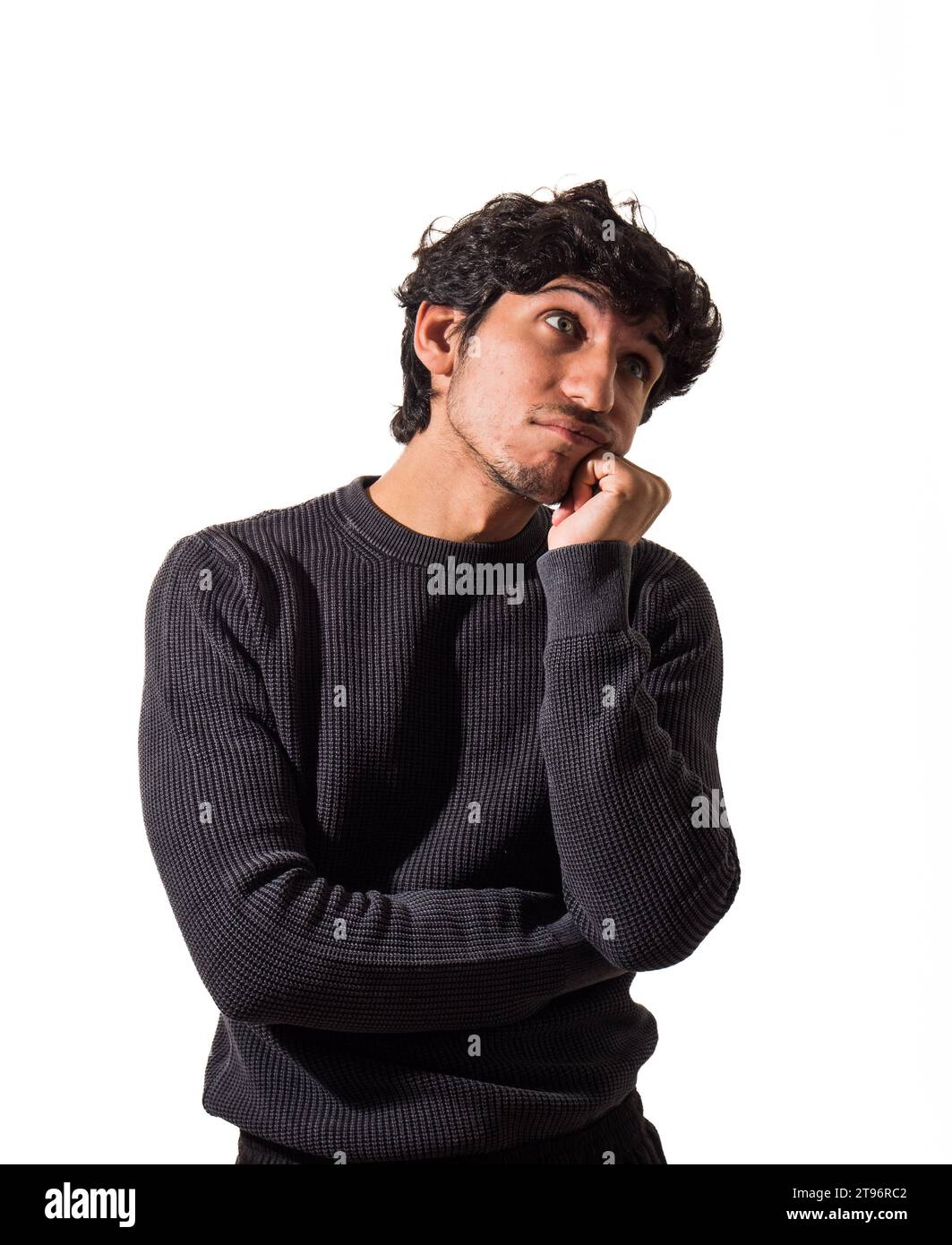 Ein Mann mit lockigen Haaren, der einen schwarzen Pullover trägt, denkt, enttäuscht oder traurig, im Studio Stockfoto