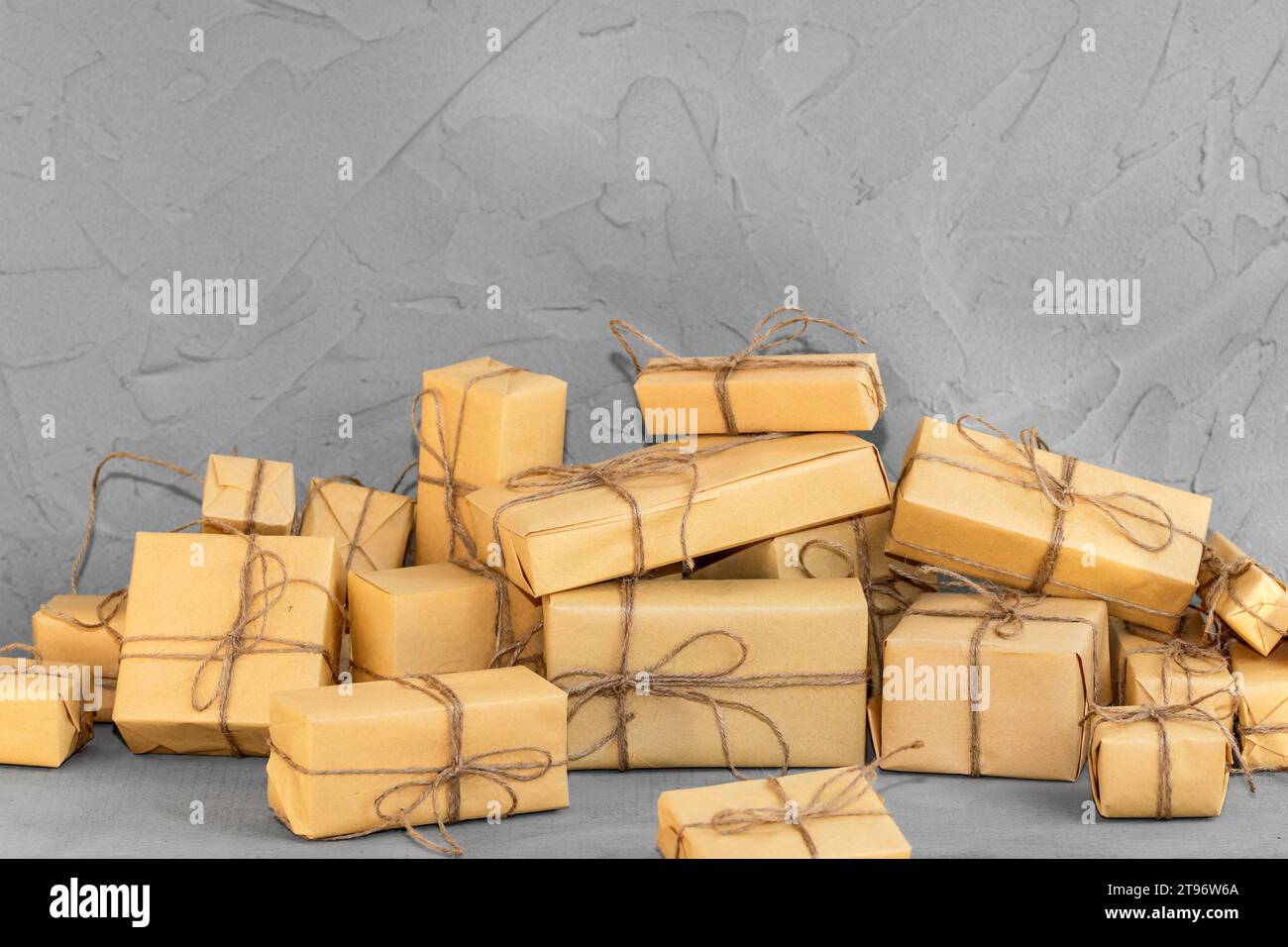 Weihnachtsgeschenkboxen auf neutralgrauem Tischhintergrund. Gratulationspostkarte, Mockup mit Präsenzanhänger, minimalistischer Stil Stockfoto