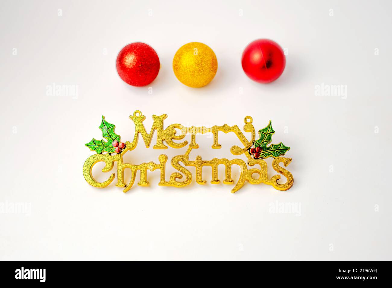 Gelb – Symbol für frohe Weihnachten vor weißem Hintergrund mit Weihnachtsbällen Stockfoto