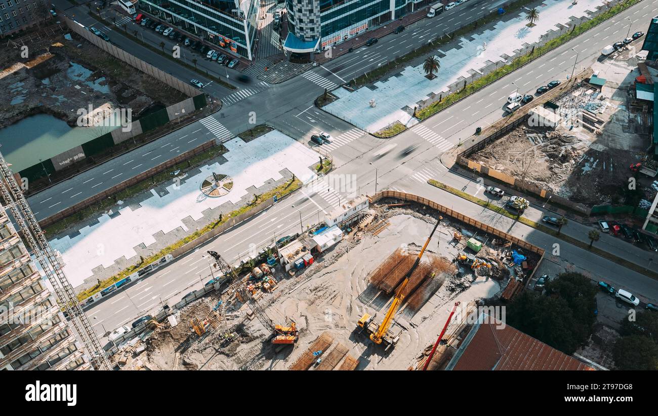 Straßenverkehr in der Nähe der Baustelle. . Stadtverkehr in der Nähe von Hochhäusern. Erhöhte Aussicht. Baukräne und Bagger Stockfoto