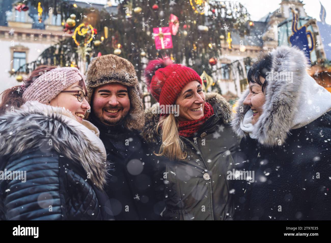 Glückliche Freunde versammelten sich auf einem festlichen Weihnachtsmarkt im Schnee Stockfoto
