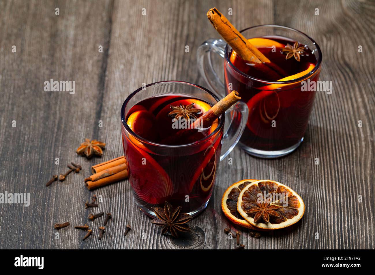 Glas Glühwein mit Orangenscheibe. Glühwein und Zutaten auf einem Holztisch. Handgeführte Aufnahmen Stockfoto