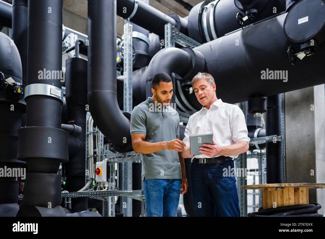 Mitarbeiter und Geschäftsmann mit digitalem Tablet im Werk Stockfoto