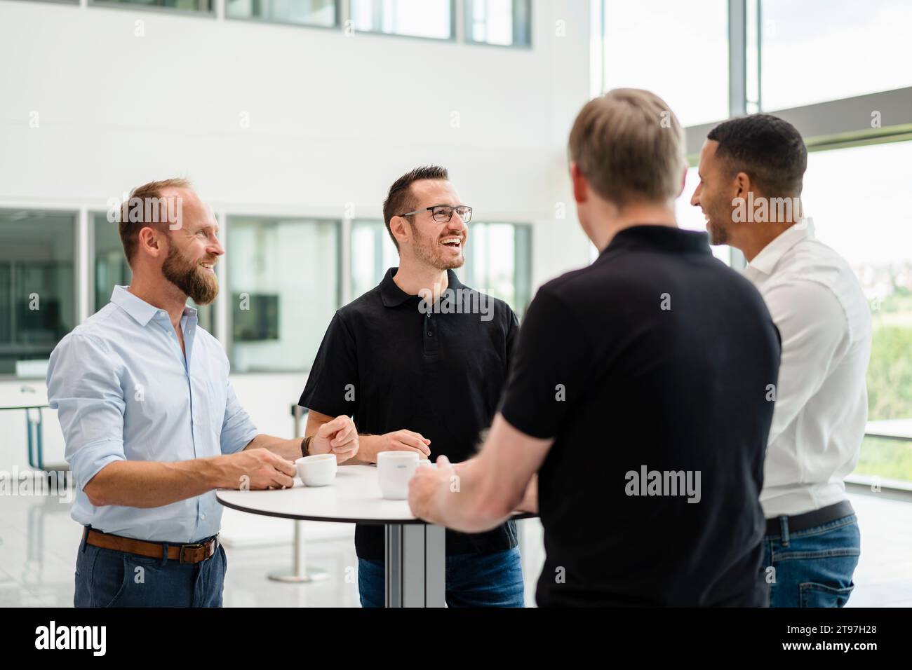 Gruppe von Geschäftsleuten, die sich bei einer informellen Besprechung im Bürosaal mit einer Tasse Kaffee treffen Stockfoto