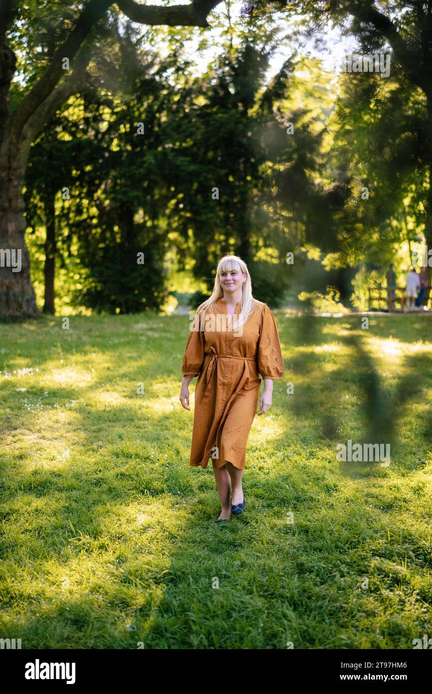 Lächelnde Frau, die im Park auf Gras läuft Stockfoto