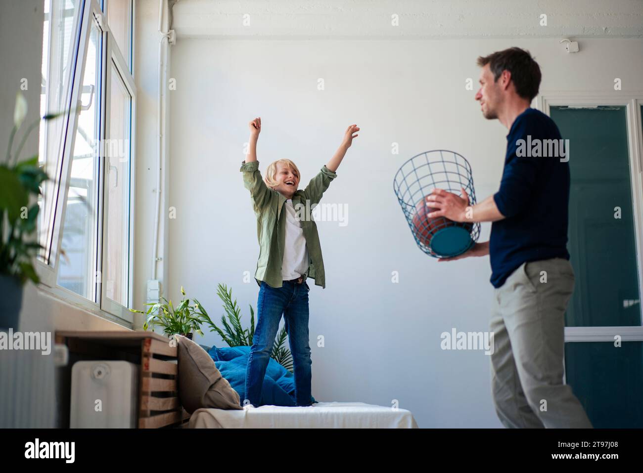 Glücklicher Sohn mit Vater, der zu Hause Papierkorb hält Stockfoto