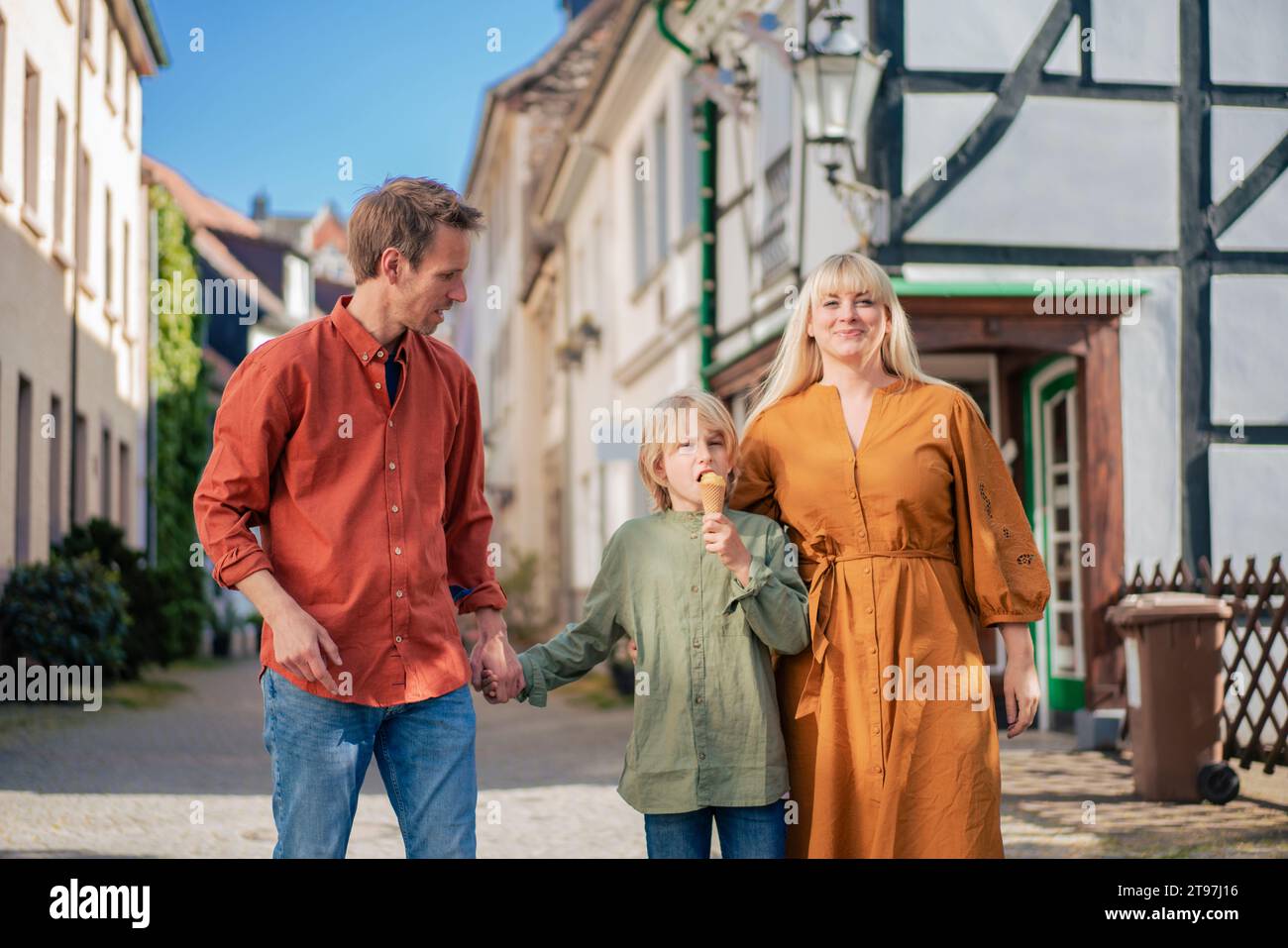 Lächelnde Eltern, die mit dem Sohn laufen und Eisbecher in der Stadt essen Stockfoto