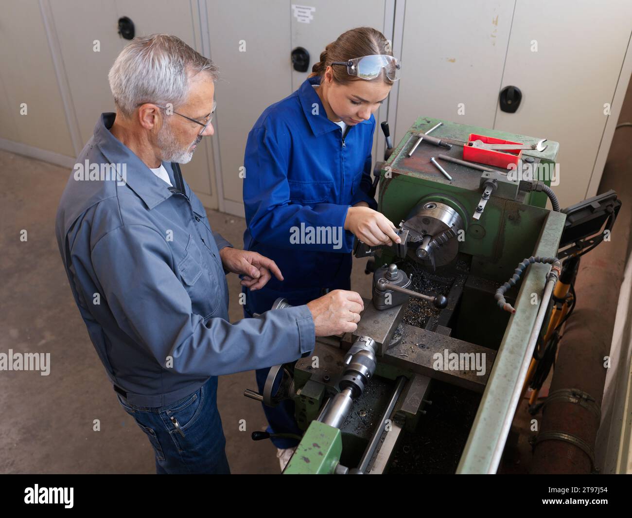 Schulungsleiter unterrichtet den Trainee in der Werkstatt mit Drehmaschine Stockfoto