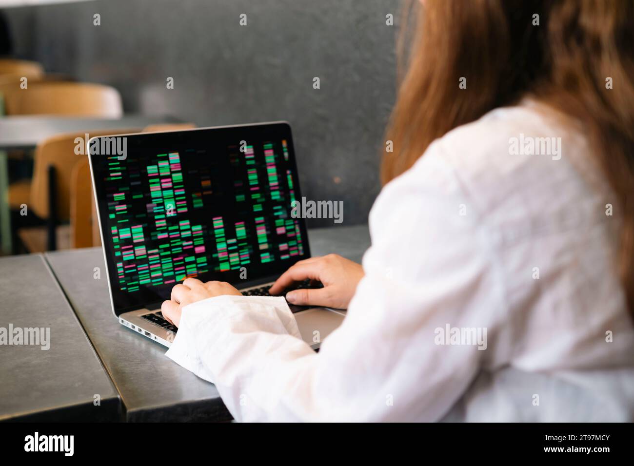 Junge Geschäftsfrau, die am Arbeitsplatz am Laptop codiert Stockfoto