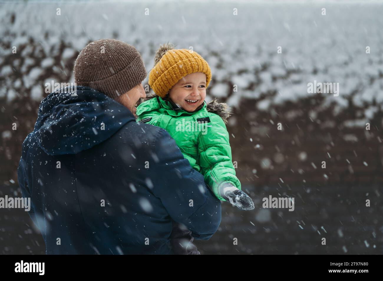 Glücklicher Junge, der im Winter Schnee mit Vater genießt Stockfoto