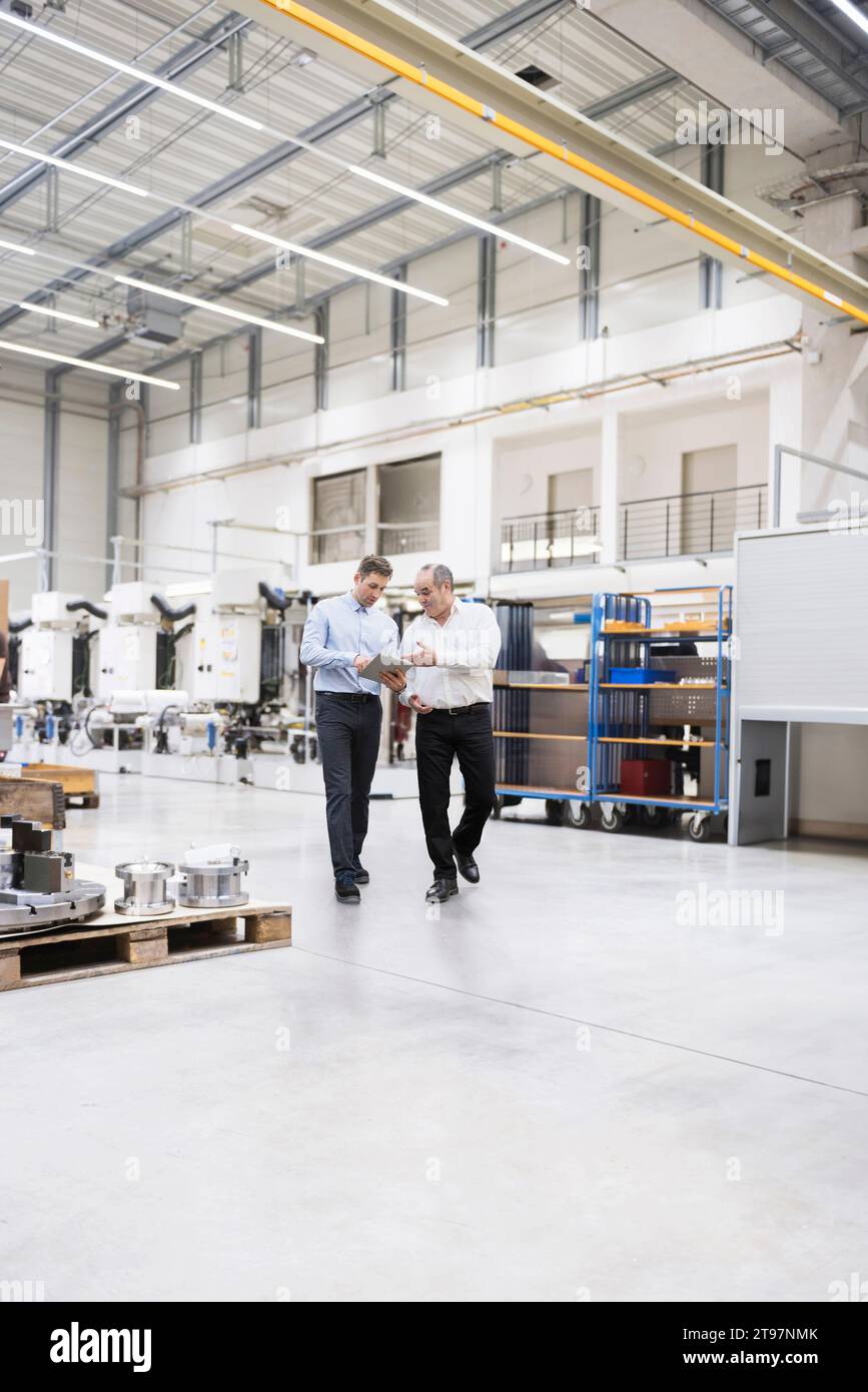 Techniker und Manager mit Tablet-PC, die sich im Werk unterhalten Stockfoto