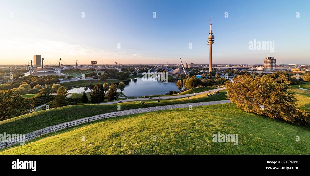 Deutschland, Bayern, München, Panoramablick auf den Olympiapark mit Olympiaturm, BMW-Gebäude und Teich im Hintergrund Stockfoto